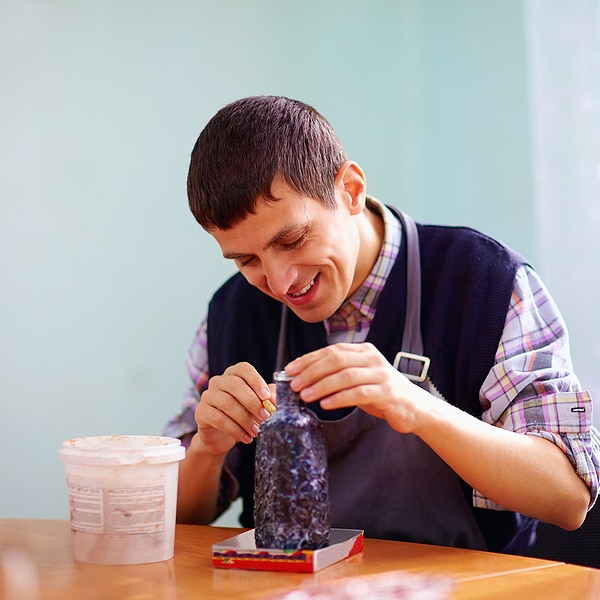 young adult man with disability engaged in craftsmanship on practical lesson in rehabilitation center